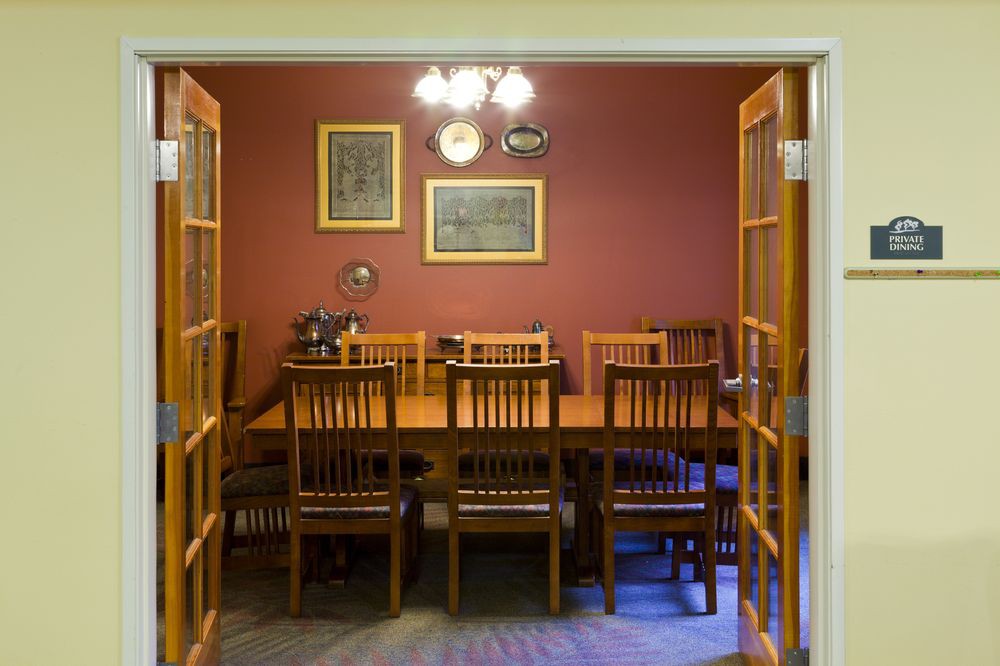 A cozy dining room with a wooden table and chairs, adorned with wall art and warm lighting.