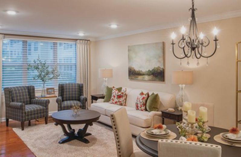 A cozy and elegantly decorated living room featuring a comfortable sofa, armchairs, a round coffee table, and a chandelier.