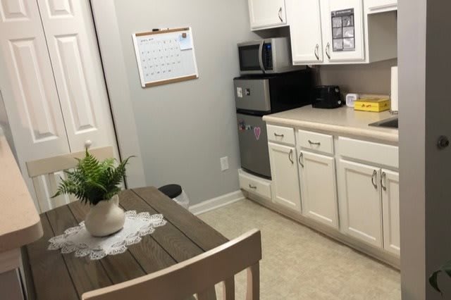 A small kitchen with a dining table, chairs, microwave, and white cabinets.