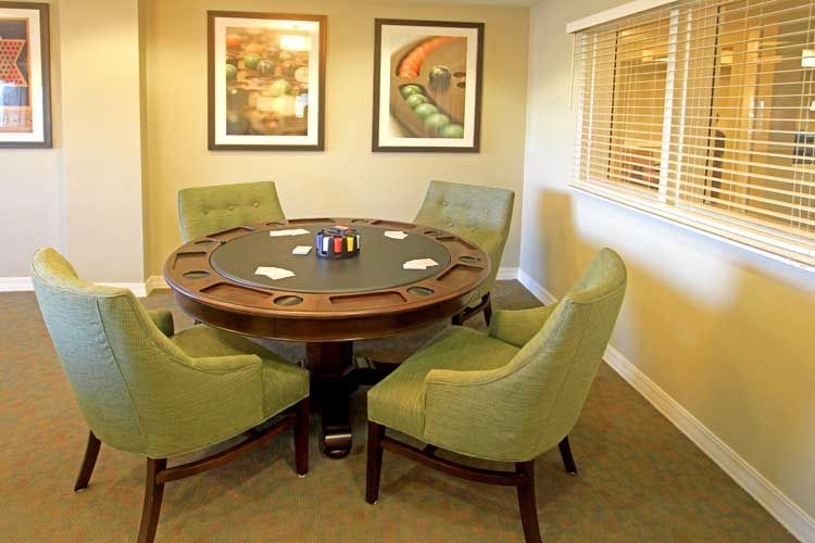 A well-appointed indoor poker table setup with green chairs.