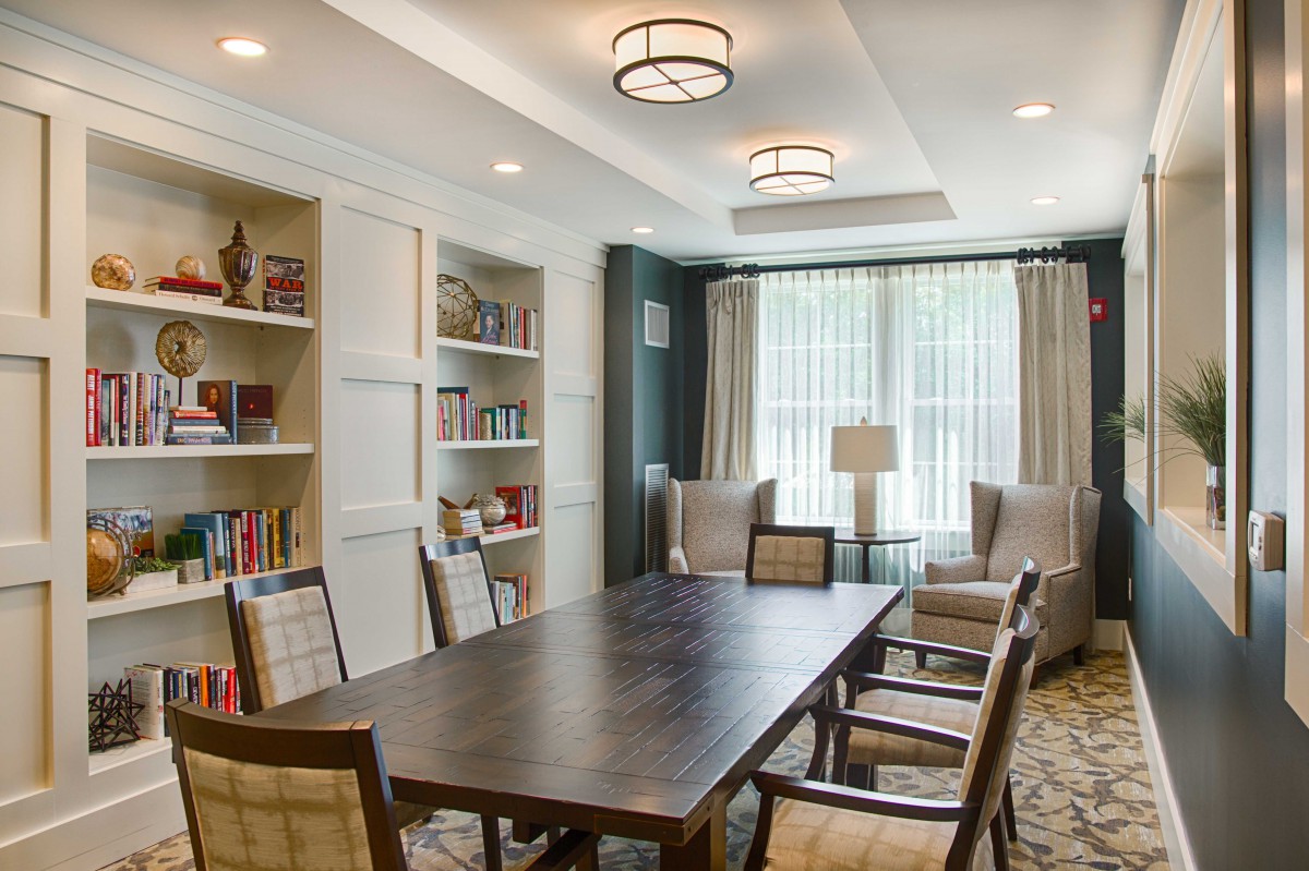 A modern conference room with a large table, chairs, and built-in bookshelves.