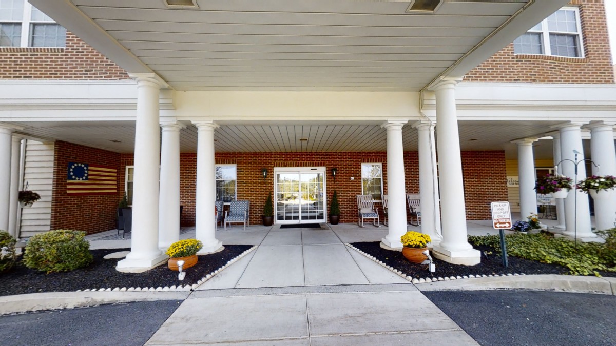 A welcoming entrance with white columns and potted flowers.