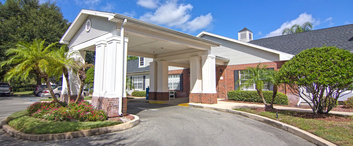 Entrance of a building with brick and white architecture under a clear blue sky.