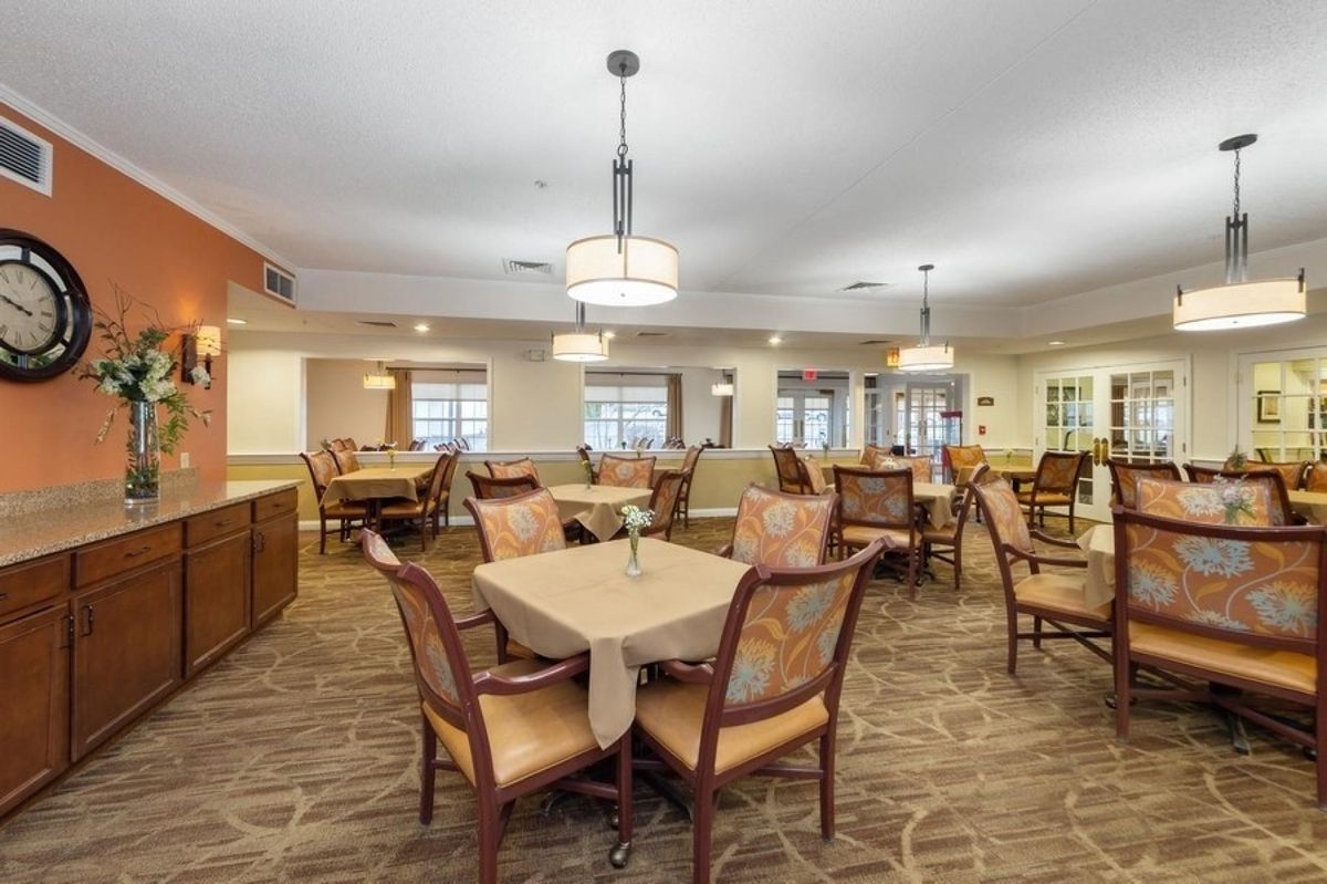 A spacious and elegantly designed dining room with neatly arranged tables and chairs, illuminated by modern light fixtures.