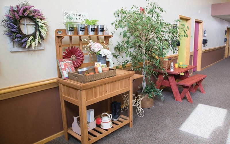 A cozy indoor gardening station with plants, a wooden shelf, and accessories for plant care.