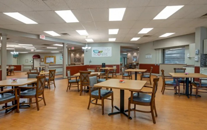 An empty dining area with neatly arranged tables and chairs under bright lighting.