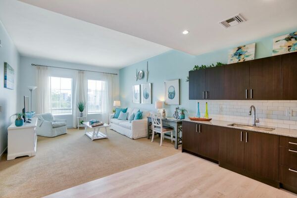 A modern, open-concept living room and kitchen area with bright decor and large windows.