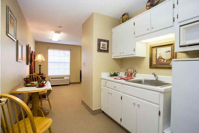 A cozy apartment kitchenette with white cabinets and a small dining area.