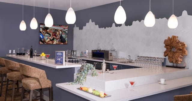 A modern bar interior with pendant lighting and a variety of drinks on the counter.