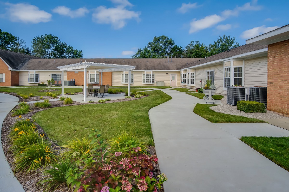 A well-maintained outdoor courtyard with a garden and walking path surrounded by a single-story building.