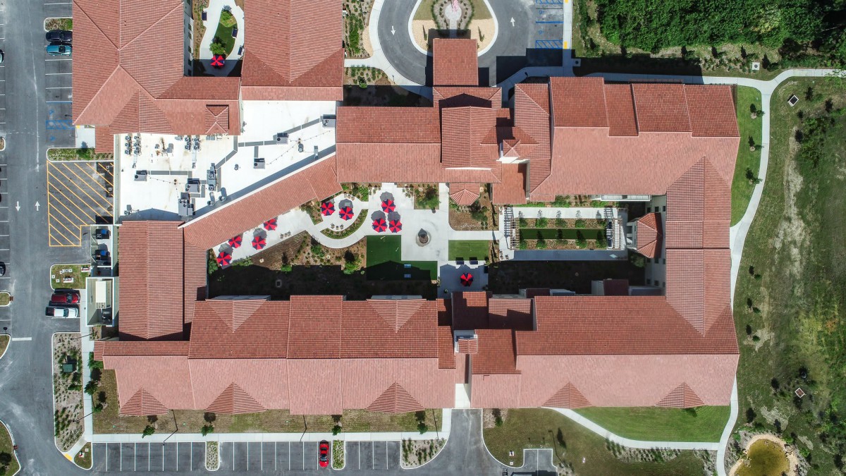 Aerial view of a complex with red-roofed buildings and landscaped areas.