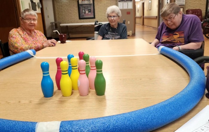 A group of people enjoying a tabletop bowling game with colorful pins.