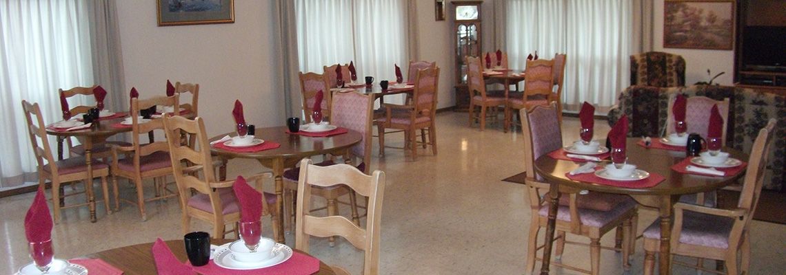 An empty restaurant dining area with neatly arranged tables and wooden chairs.