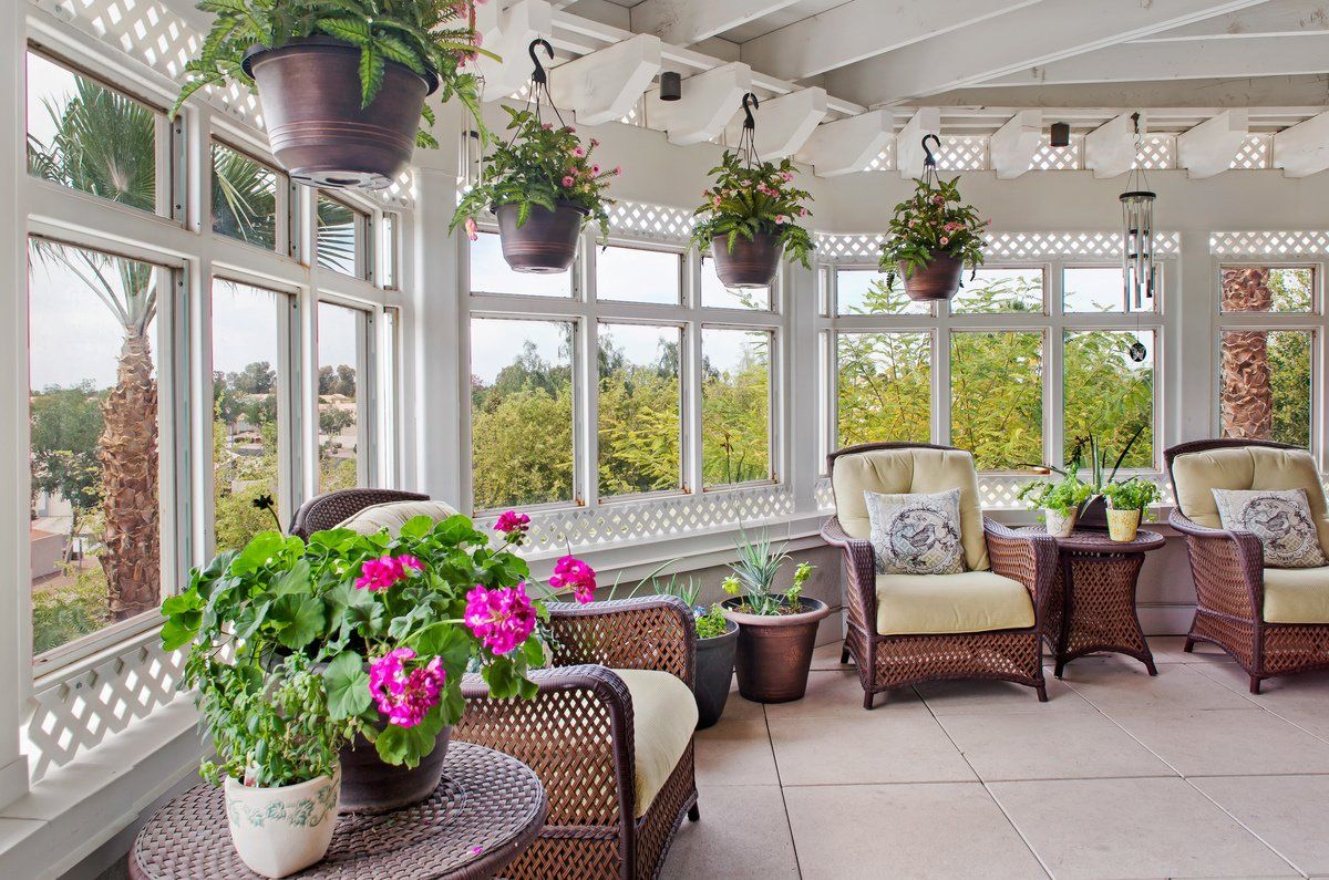 A bright and airy sunroom adorned with wicker furniture and vibrant plants.