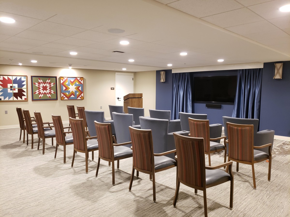 A neatly arranged conference room with chairs facing a television and projector screen.