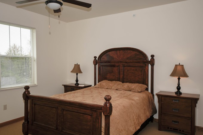 A cozy bedroom with a wooden bed, nightstands, and a ceiling fan.
