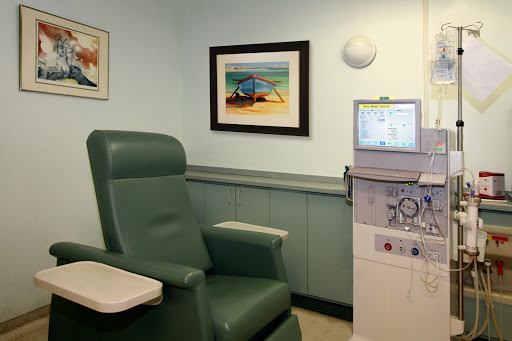 A comfortable patient chair in a medical office, accompanied by healthcare equipment and art on the walls.