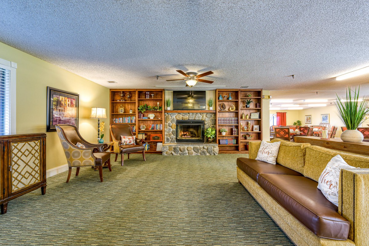 A cozy living room with a fireplace and bookshelves, featuring comfortable seating and warm lighting.