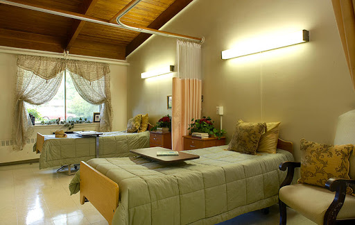 A cozy patient room in a healthcare facility, featuring two beds and warm lighting.