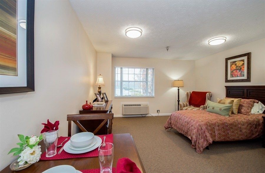 A cozy bedroom with a neatly set table, bed, and soft lighting.