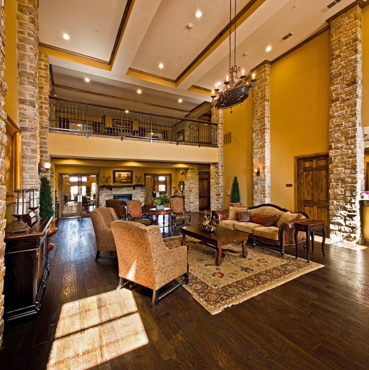 A spacious and elegant hotel lobby with a high ceiling, featuring comfortable seating, a large chandelier, and stone column accents.