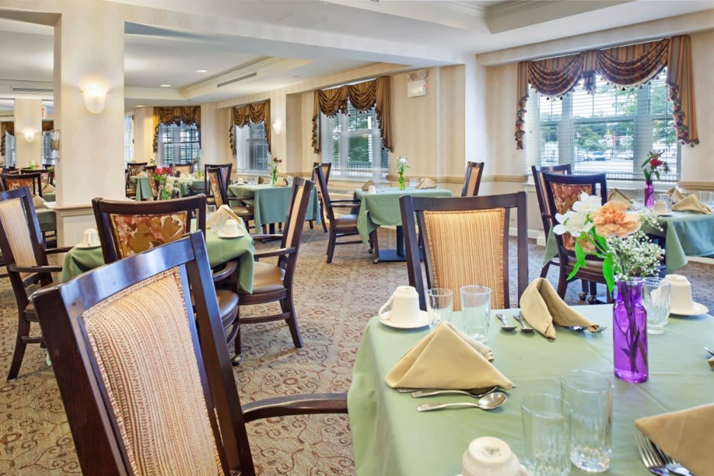 An elegant dining room with neatly arranged tables and chairs, set for a formal meal.