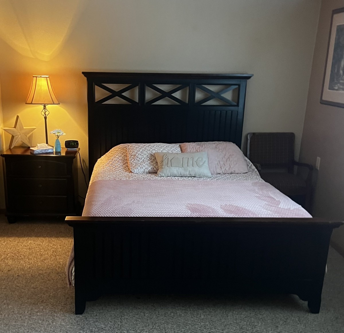 A cozy bedroom with a neatly made bed, nightstand, and a lamp.