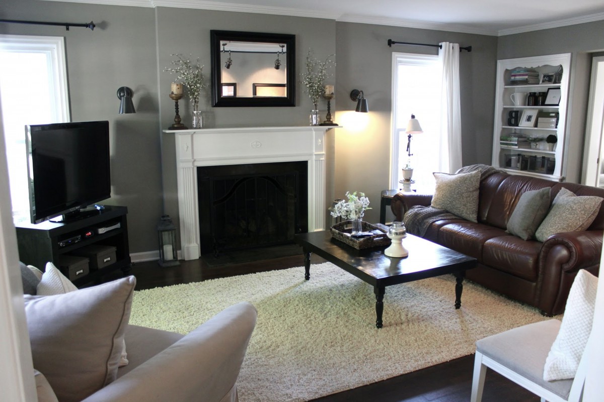 A cozy living room featuring a fireplace, leather sofa, armchair, and a coffee table with decorative items.