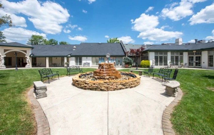 A sunny day in a courtyard with a central fountain and surrounding seating area.