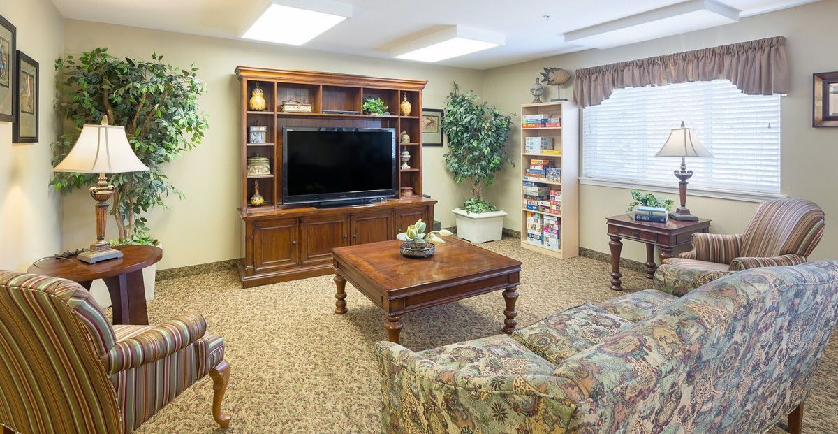 A cozy living room with a large television, wooden furniture, and decorative elements.