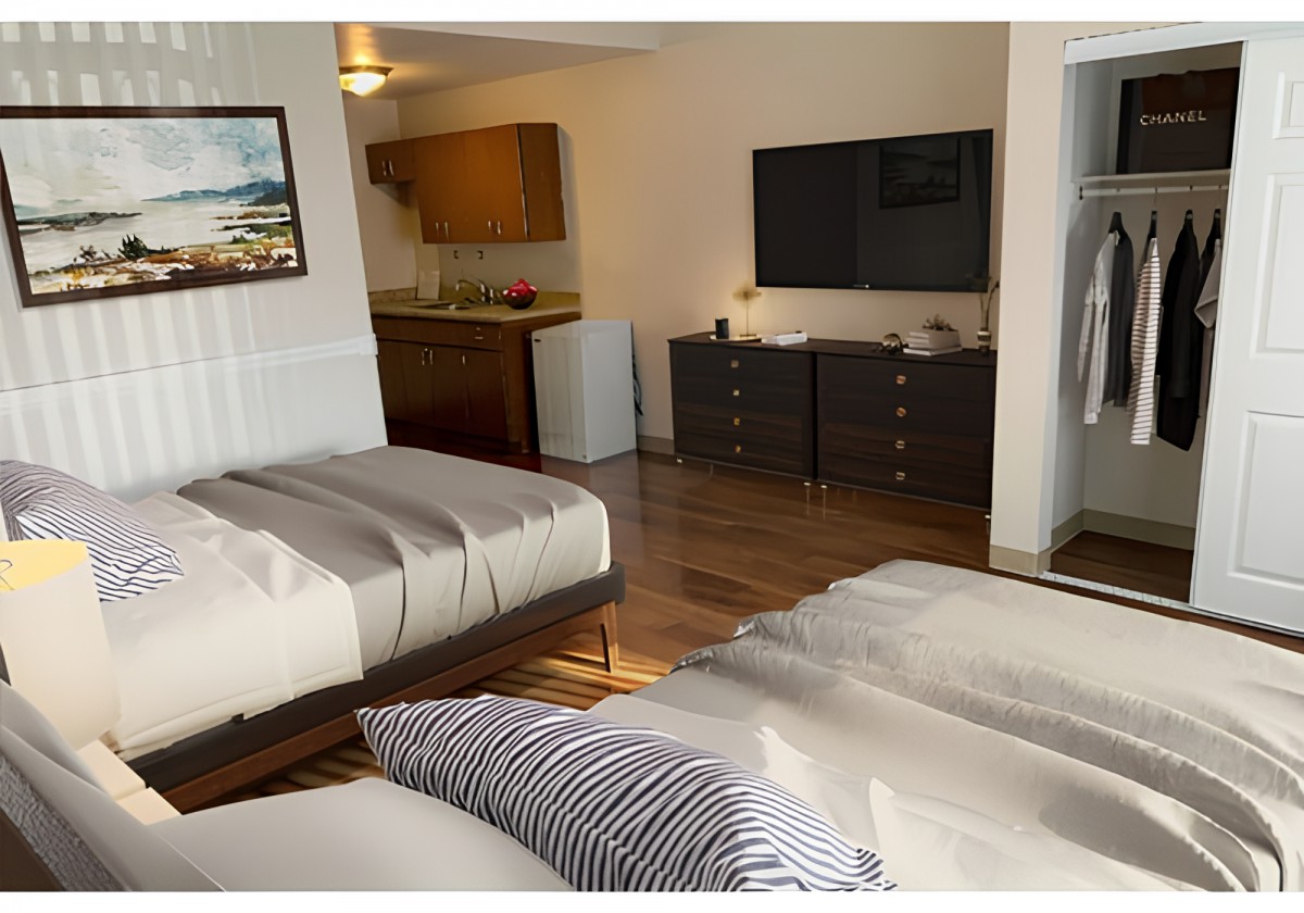 A modern hotel room with two beds, a television, a dresser, and a small kitchenette.