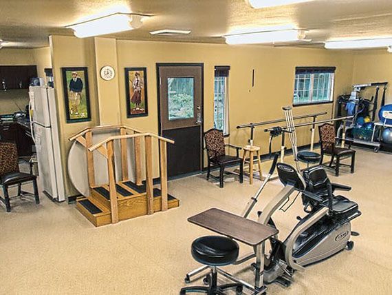 A rehabilitation therapy room equipped with various exercise machines and tools.