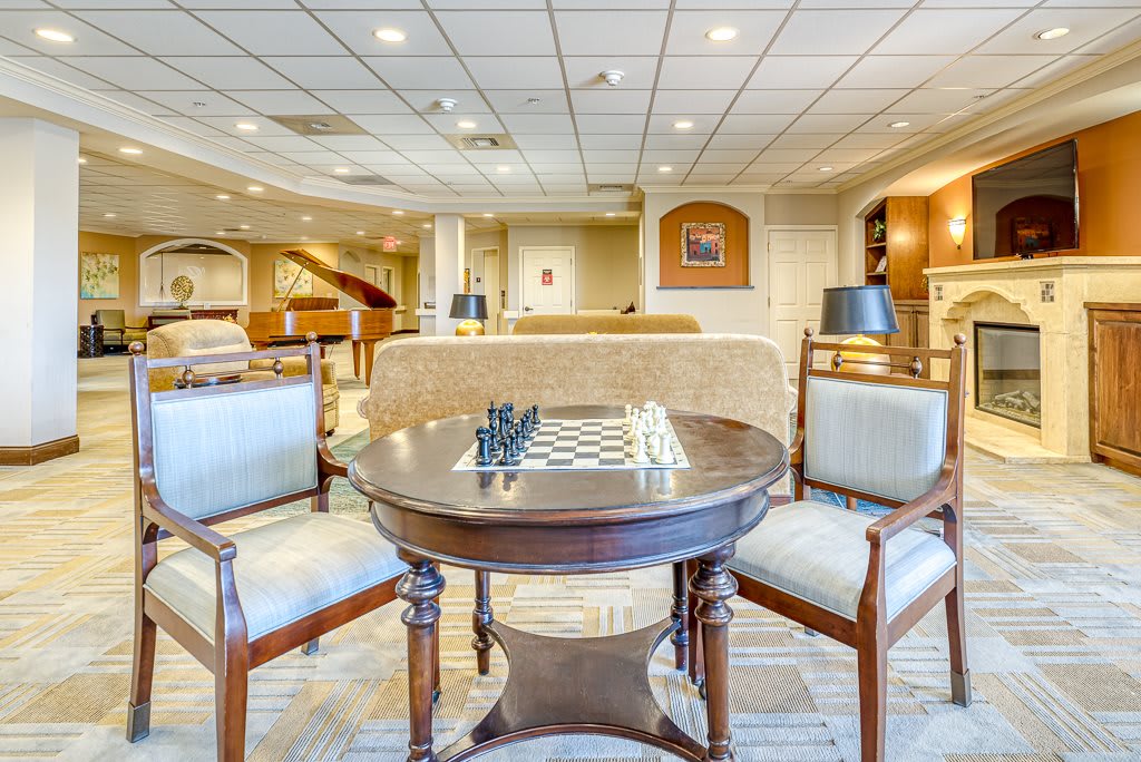 A hotel lounge area with a chessboard on a round table surrounded by comfortable seating.