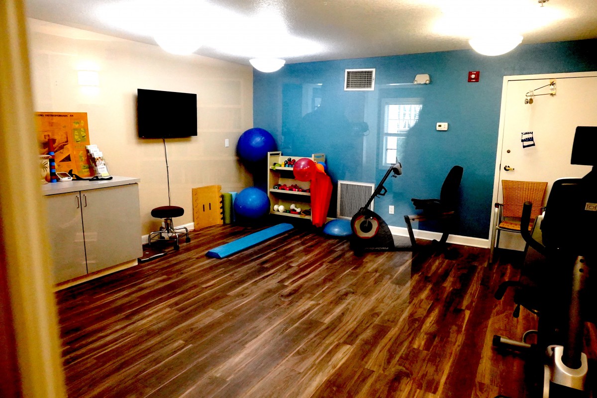 A small exercise room featuring gym equipment like a stationary bike, yoga mat, and exercise balls.