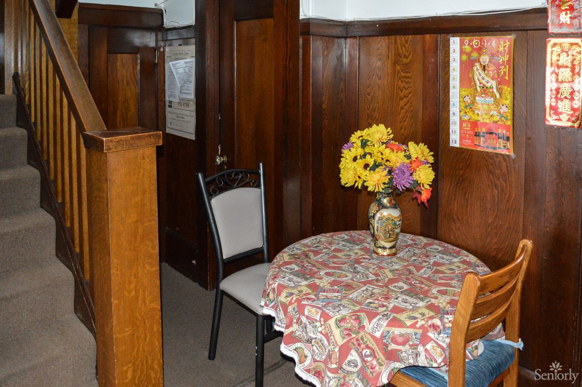 A cozy corner with a small table covered by a patterned tablecloth, featuring a vase of colorful flowers.