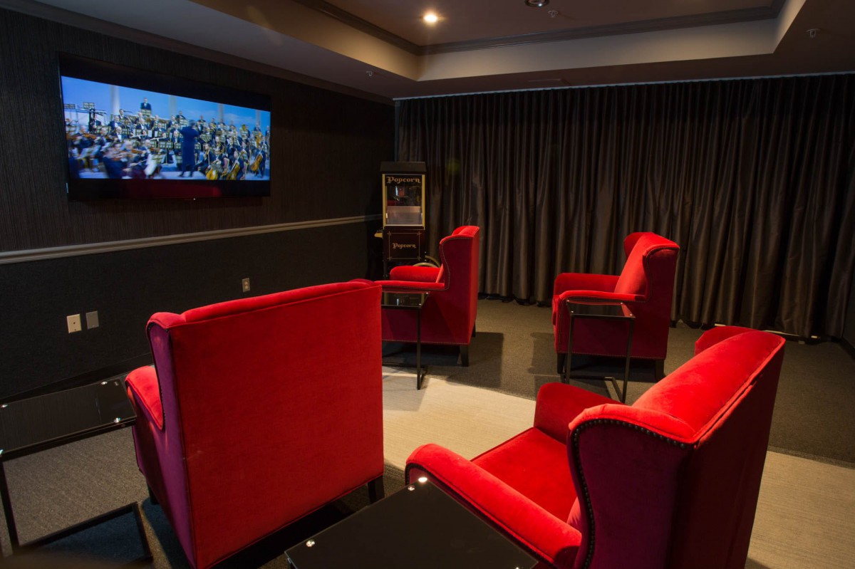 A cozy home theater room with red chairs and a television on the wall.