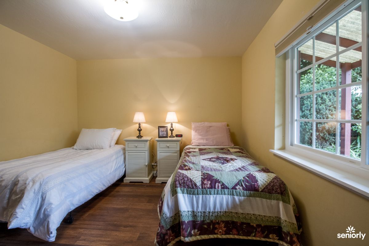 A cozy bedroom with two twin beds, a shared nightstand, and soft lighting from table lamps.
