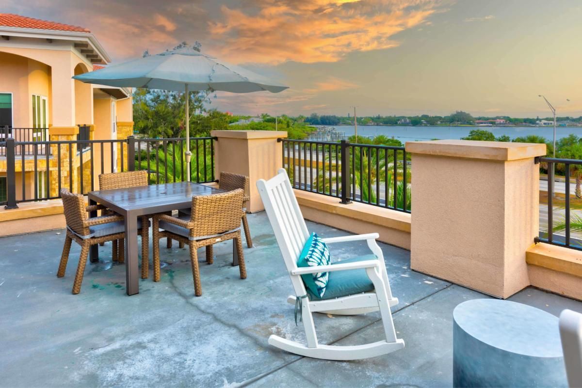 A cozy patio with a rocking chair and table set overlooking a scenic sunset view.