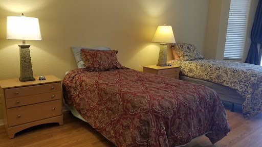 A cozy bedroom featuring twin beds with decorative bedspreads and a bedside lamp.