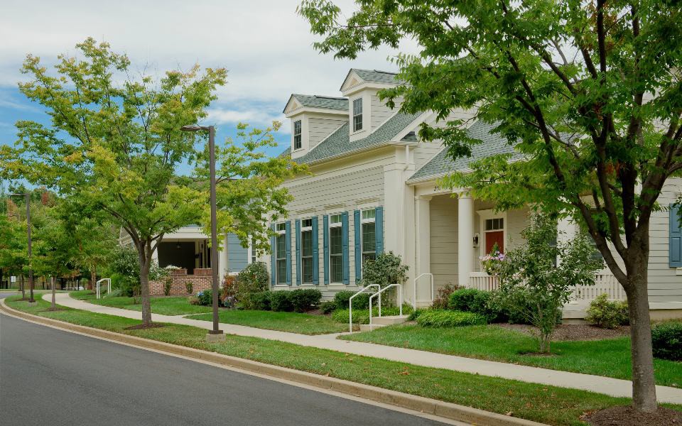 A suburban residential neighborhood with houses, trees, and a sidewalk.