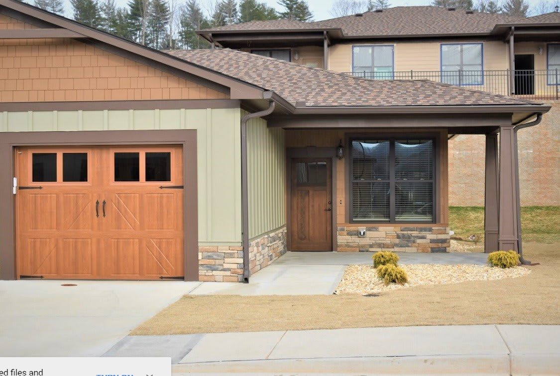 A modern house with a wooden garage door and driveway.