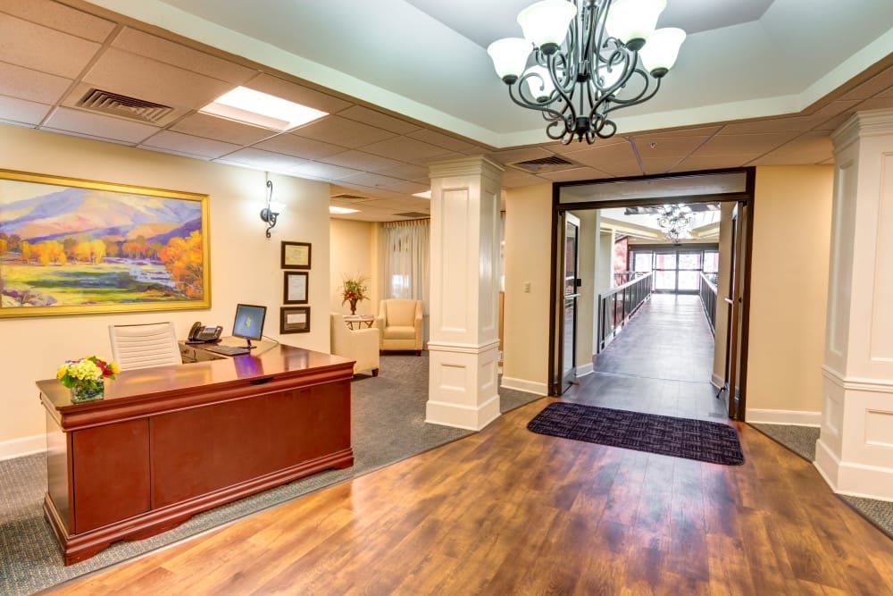 A spacious and elegantly designed reception area with a wooden desk and chandelier lighting.