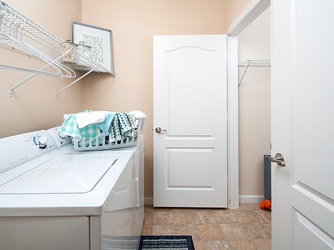 A tidy laundry room with a washing machine, dryer, and a basket of folded towels.