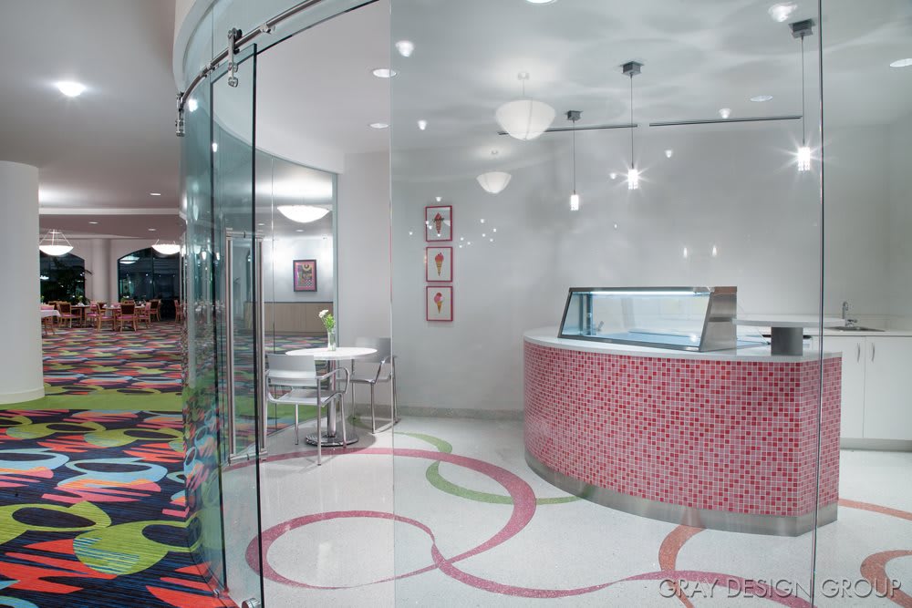 A modern ice cream shop interior with colorful flooring and glass walls.