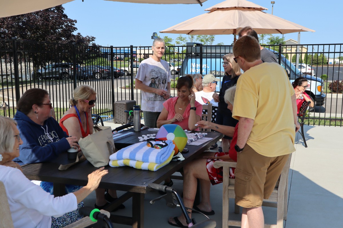 A group of people gathered around a table outdoors on a sunny day.
