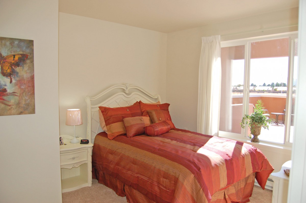 A cozy bedroom with warm-colored bedding and natural light streaming in.