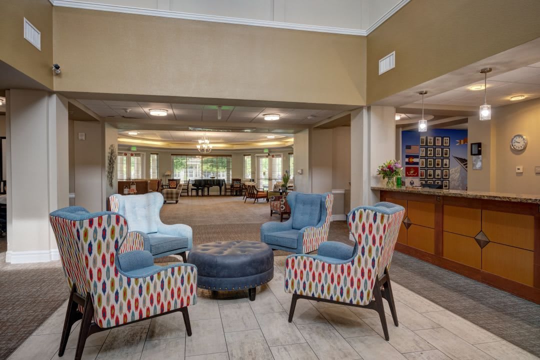A cozy seating area featuring colorful armchairs and a round ottoman in a spacious lounge.