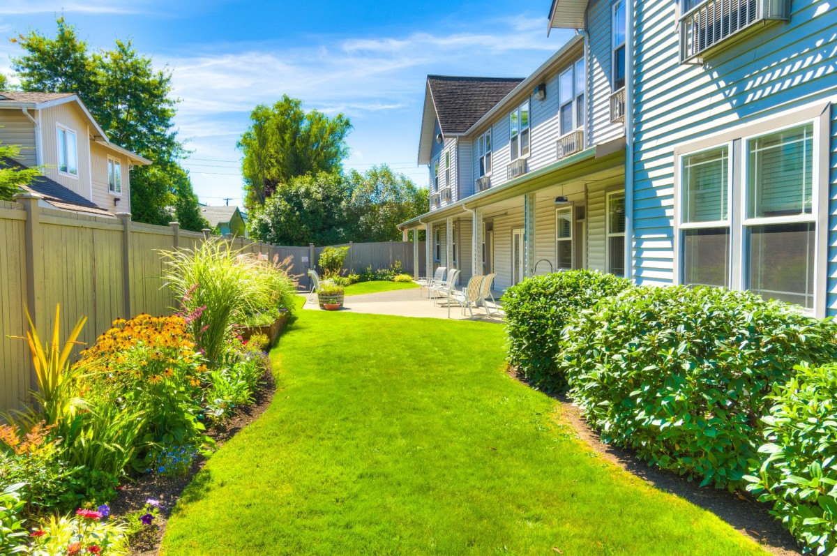 A sunny day view of a residential house with a well-maintained garden and lawn.