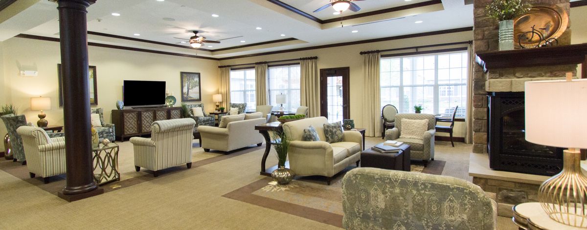 A spacious and elegantly furnished living room with large windows, multiple sofas, and tasteful decor.
