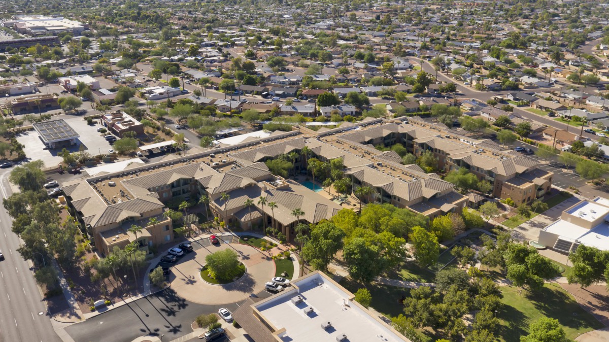 Aerial view of a suburban residential area with numerous buildings, roads, and greenery.